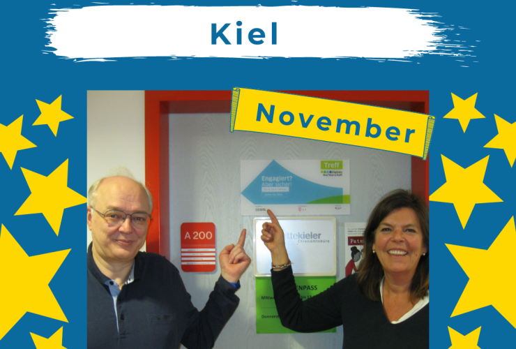 Auf dem Bild sieht man einen Mann und eine Frau, die mit dem Zeigefinger auf eine DiNa-Check Plakette hinter ihnen zeigen.